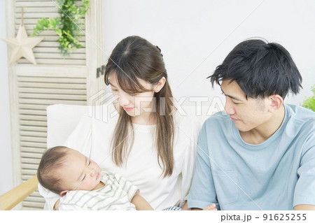 リビングで昼寝する赤ちゃんを見る両親 リビングで昼寝する赤ちゃんを見る両親 91625255