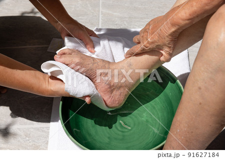 Female caregiver wipes the elderly woman feet by towel. Female caregiver wipes the elderly woman feet by towel. 91627184