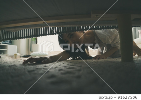 ベッドの下を覗き込む女性 91627506