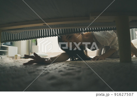 ベッドの下を覗き込む女性 91627507