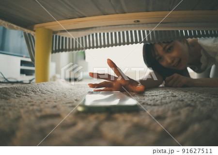 ベッドの下でスマホを発見した女性 ベッドの下でスマホを発見した女性 91627511
