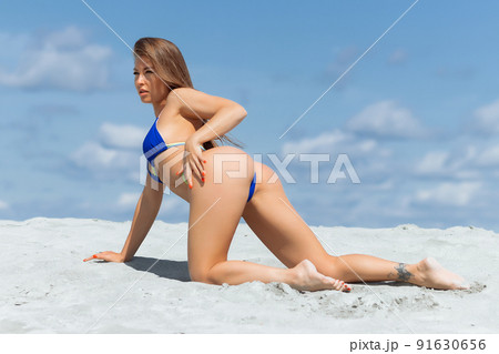 Graceful woman in bikini on sandy beach Graceful woman in bikini on sandy beach 91630656