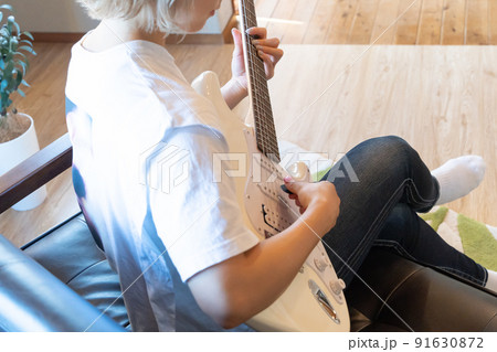 白いエレキギターを弾く若い女性 91630872