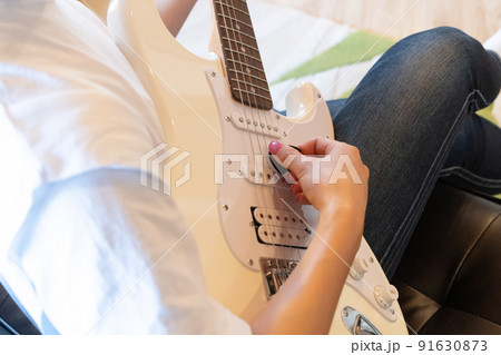 白いエレキギターを弾く若い女性 白いエレキギターを弾く若い女性 91630873