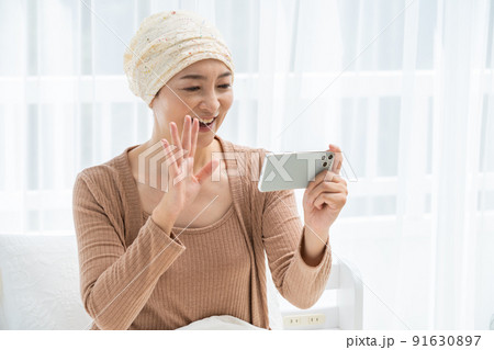 ベッドでスマホを見る医療用帽子をかぶったミドル女性 91630897