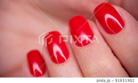 Female hand with bright red glossy gel polish 91631902