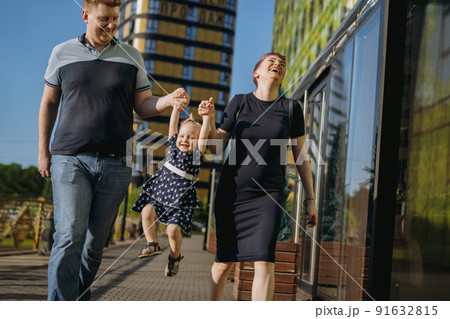 Happy caucasian family couple enjoy walking with daughter. mother happily laughing Happy caucasian family couple enjoy walking with daughter. mother happily laughing 91632815