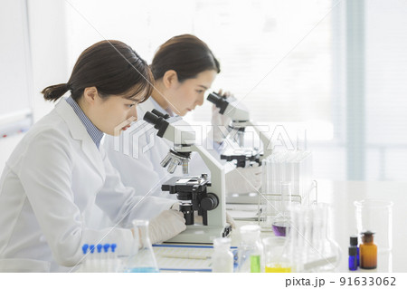 顕微鏡を覗く白衣の女性 研究 実験 91633062