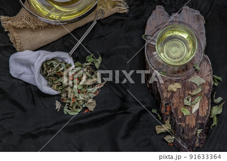 A Cup of pandan leaf tea, indian marsh fleabane plant leaves with Safflower dried (Saffron substitute) at dark background. 91633364