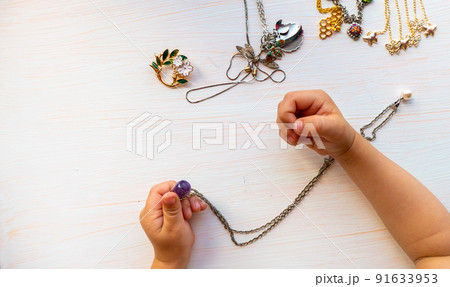 childrens hands play with light summer bijouterie, on white background. concept of womens happines. childrens hands play with light summer bijouterie, on white background. concept of womens happines. 91633953