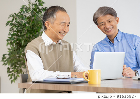 自宅のリビングでビジネスの話をするシニア男性2人 自宅のリビングでビジネスの話をするシニア男性2人 91635927