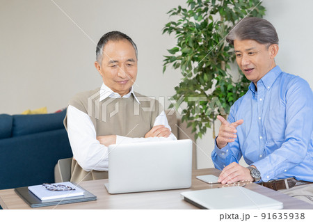 自宅のリビングでビジネスの話をするシニア男性2人 91635938