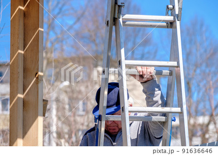Senior gray-haired builder descends the stairs against the blue sky. 91636646