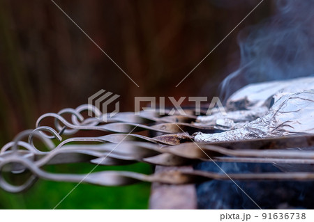 Abstract highly blurred view of metal skewers lying on a grill over coals. 91636738