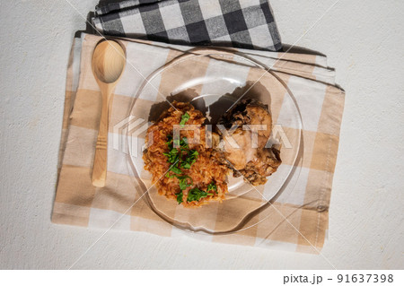 Bowl of east African Jollof Rice garnished with pieces of roasted chicken - top view 91637398