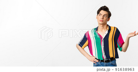 Confused gay man looking left at something strange, raising hand clueless and puzzled, standing over white background Confused gay man looking left at something strange, raising hand clueless and puzzled, standing over white background 91638963