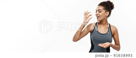 Healthy and Fitness concept - Closeup portrait of beautiful African American taking a pill of Cod liver oil. Isolated on white studio background. Healthy and Fitness concept - Closeup portrait of beautiful African American taking a pill of Cod liver oil. Isolated on white studio background. 91638993