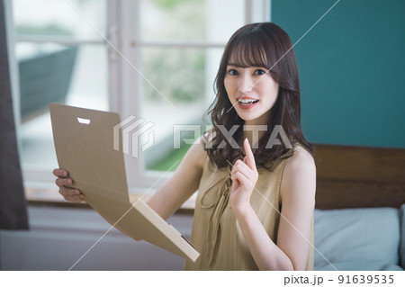 部屋で通販の荷物を確認をする若い女性のライフスタイルイメージ 91639535