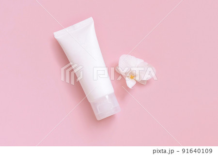 White cream tube near white orchid flower on light yellow top view. Mockup. Skincare product White cream tube near white orchid flower on light yellow top view. Mockup. Skincare product 91640109