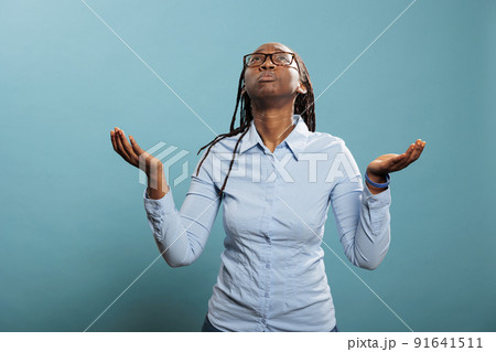 Faithful african american woman with palms faced to sky pleading and begging to have her sins forgiven. Religious and spiritual young person praying for a better and forgiving world. Studio shot 91641511