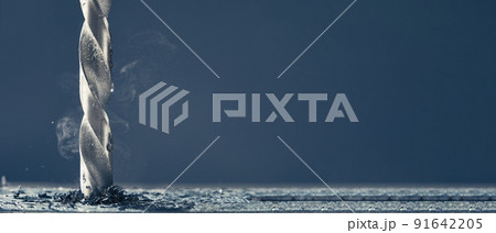 Metal drill bit make holes in aluminum billet on industrial drilling machine with shavings. Photo with copy space. 91642205