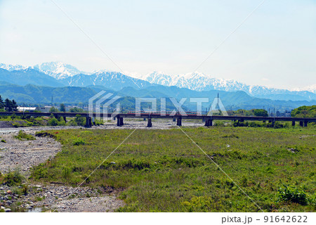 【富山県魚津市】早月橋から望む峰々と通過する電車 91642622