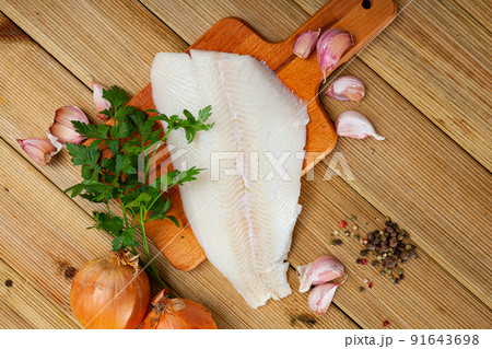 Fillet of raw halibut fish with garlic and greens 91643698