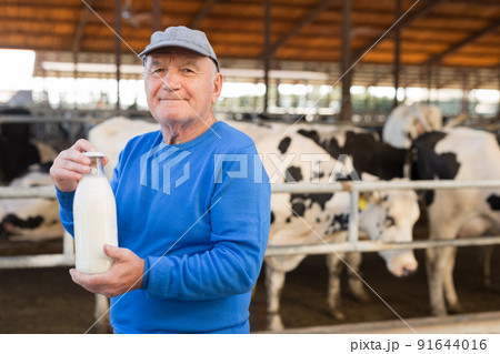 Positive aged man dairy farm owner holding bottle of milk 91644016