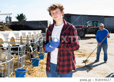 Young farm worker with bottle of milk in hands standing outdoors Young farm worker with bottle of milk in hands standing outdoors 91644027