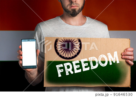 Concept of freedoms and human rights. A man with a cardboard and a phone in his hand. The Flag of India. Text freedom and mock up Concept of freedoms and human rights. A man with a cardboard and a phone in his hand. The Flag of India. Text freedom and mock up 91646530