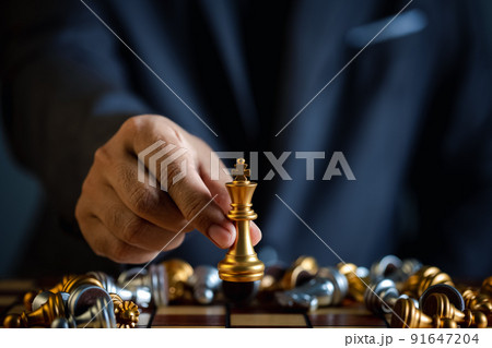 closeup hand of businessman holding chess piece in competition play 91647204