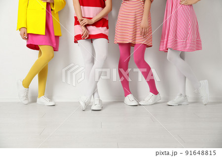 Women wearing colorful tights near white wall, closeup 91648815