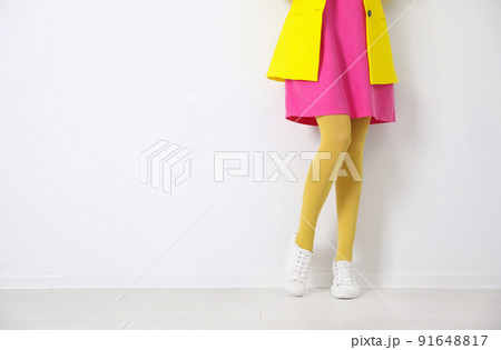 Woman wearing yellow tights near white wall, closeup. Space for text 91648817