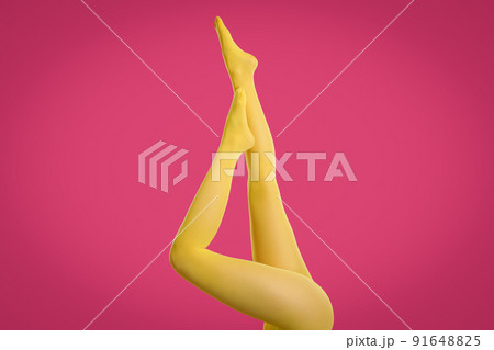 Woman wearing yellow tights on crimson background, closeup of legs 91648825