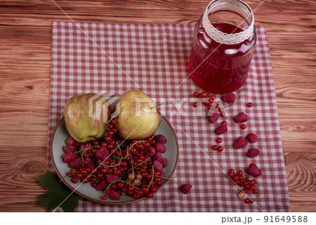 Compote, red currants, raspberries and apples on an old wooden table. Compote, red currants, raspberries and apples on an old wooden table. 91649588