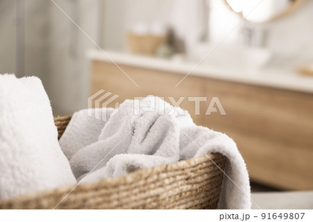 Wicker basket with clean towels in bathroom, closeup 91649807