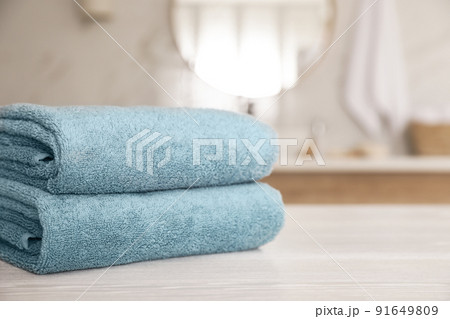 Stack of clean towels on white wooden table in bathroom. Space for text 91649809