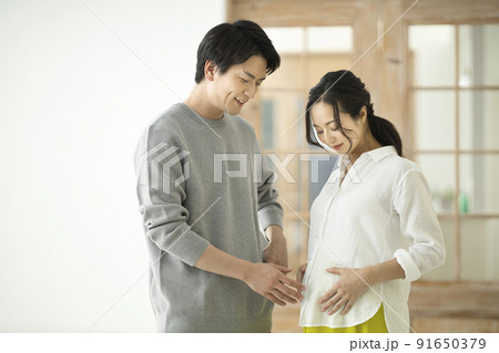 妊婦のおなかに手を添えて話すカップル 妊婦のおなかに手を添えて話すカップル 91650379