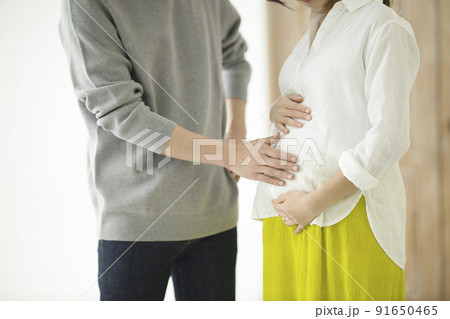 妊婦のおなかに手を添えて話すカップル 妊婦のおなかに手を添えて話すカップル 91650465
