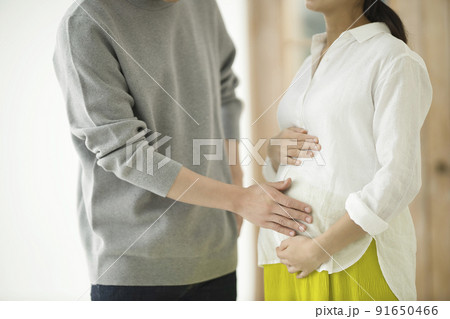 妊婦のおなかに手を添えて話すカップル 妊婦のおなかに手を添えて話すカップル 91650466