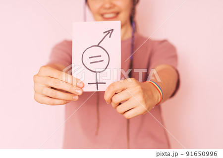 Girl holding paper with gender equality sign against pink background 91650996