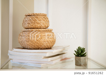 Close-up of a round straw box with a lid on a white shelf. Close-up of a round straw box with a lid on a white shelf. 91651262