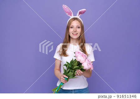 Cute young woman with pink easter bunny ears on purple background in white 91651346