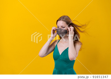 Beautiful young woman protection mask wearing for coronavirus disease on yellow 91651347