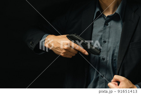 拳銃を構えるスーツの人物 91651413
