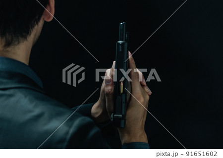 拳銃を構えるスーツの人物 91651602