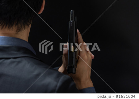 拳銃を構えるスーツの人物 91651604