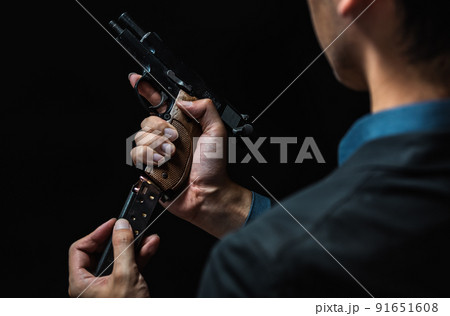 拳銃を構えるスーツの人物 91651608