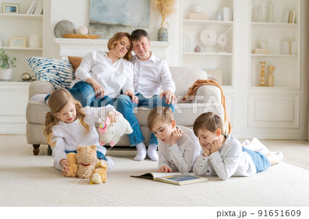Happy caucasian parents are relaxing on cozy sofa in living room at home. Small 91651609