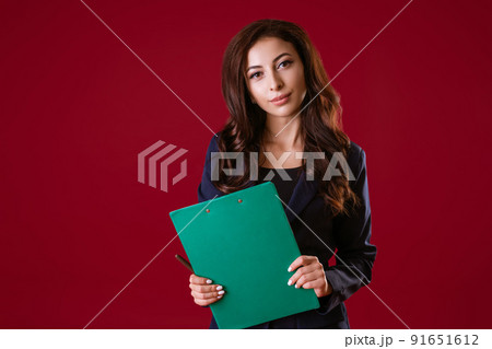 A woman director is holding documents and smiling on a red background. 91651612